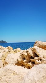 Rocks on beach against clear blue sky