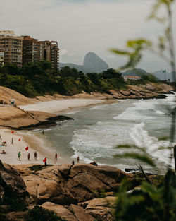 People on beach by mountain against sky