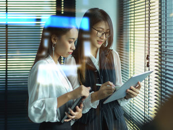 Woman looking at camera while standing against window