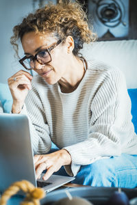 Friends using laptop while sitting on sofa at home