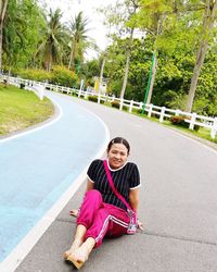 Portrait of smiling woman sitting on road