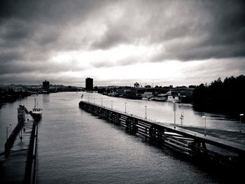 Pier on river against cloudy sky