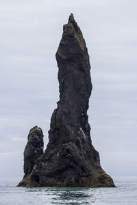 Rock formation by sea against sky