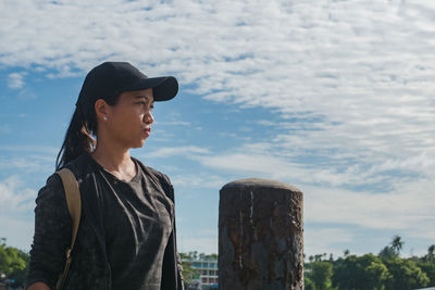 Side view of young woman looking away against sky