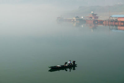 Man on boat in lake during foggy weather