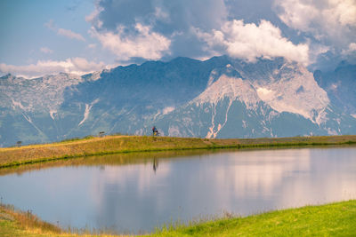 Man riding a mountain bike next to lake in sunset light in the austrian alps, saalbach, austria