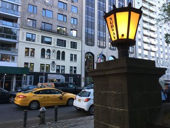 Illuminated street light against building in city