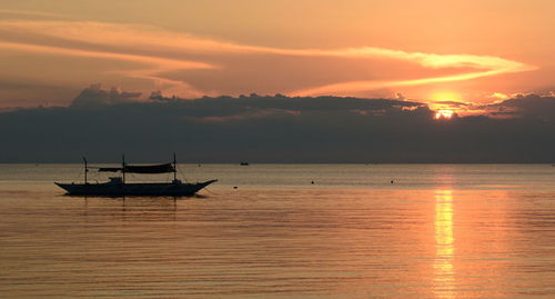 Silhouette sailboat on sea against sky during sunset