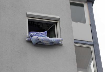 Low angle view of clothes hanging on window against building