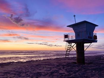 Lifeguard hut on beach against sky during sunset