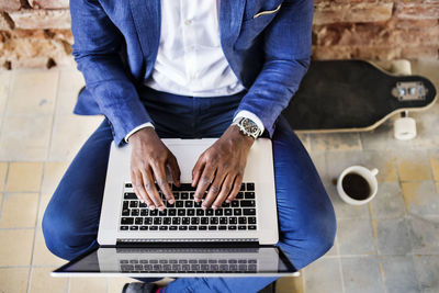 Top view of businessman sitting on longboard using laptop