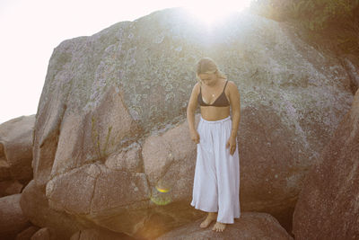 Rear view of woman standing against rock