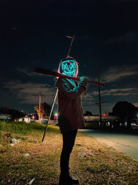 Rear view of man standing on illuminated land at night