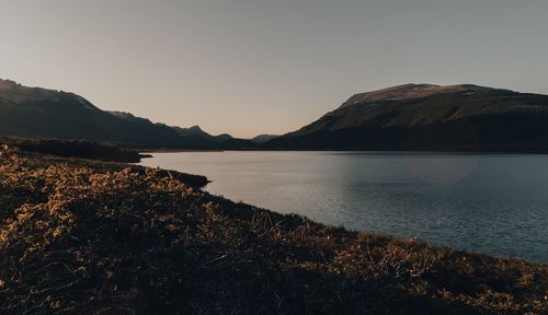 Scenic view of lake by mountains against clear sky