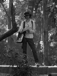 Full length of young man standing on tree trunk in forest