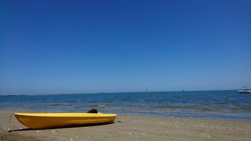 Boat on beach against clear blue sky