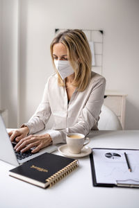 Woman using phone while sitting on table