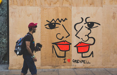 Rear view of man standing against graffiti wall