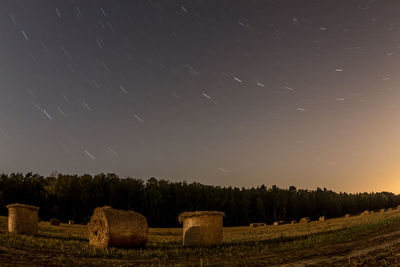 Hay bales on field against sky at night