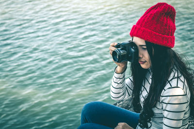 Young woman photographing by lake