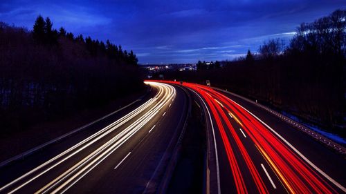 High angle view of light trails on highway against sky at night