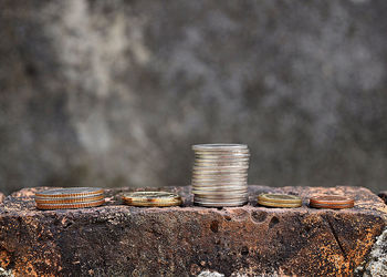 Close-up of coins stacked on brick against wall