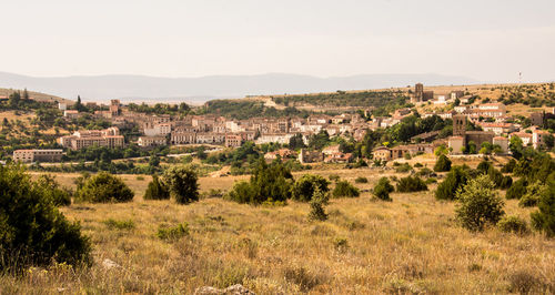 Trees and buildings in city against clear sky