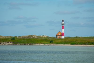 Lighthouse by sea against sky