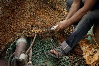 Low section of man cutting fishing net