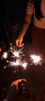 Midsection of woman holding sparkler at night