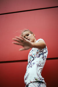 Portrait of young woman standing against yellow wall