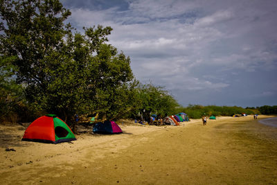 People relaxing on beach against sky