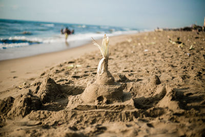 Stick on sandcastle at beach against sky