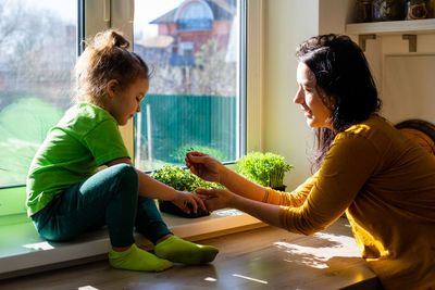 Side view of mother and woman sitting at home