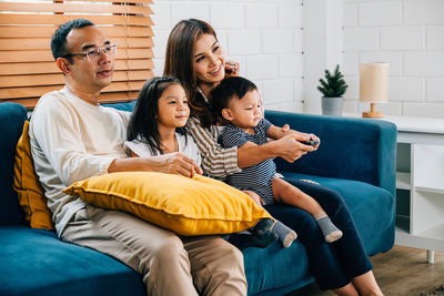 Portrait of woman using mobile phone while sitting on sofa at home