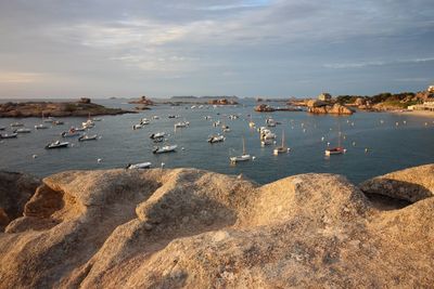 Boats on sea against cloudy sky