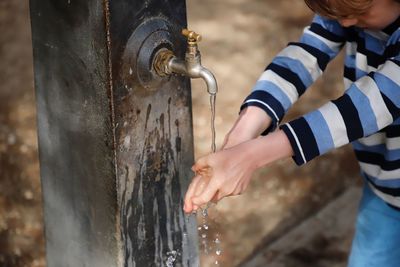 Midsection of boy washing hands at outdoors