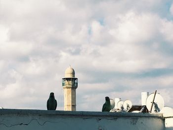 Low angle view of seagull perching on lighthouse against sky