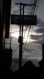 Low angle view of silhouette electricity pylon against sky at sunset