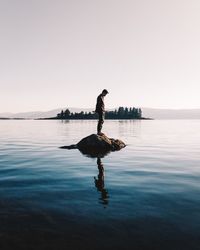 Full length of man standing on lake against clear sky