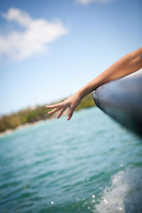 Close-up of woman hand against sea