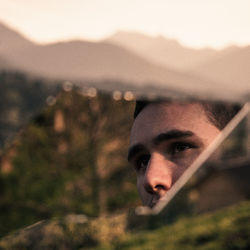 Reflection of man on broken mirror against trees