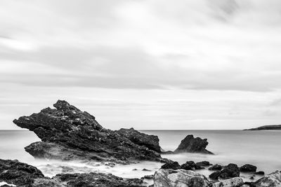 Rock formation on beach against sky
