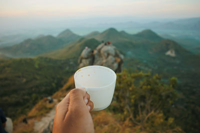 Midsection of person holding ice cream against mountains