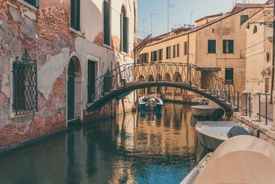 Arch bridge over canal amidst buildings in city