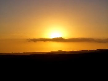 Scenic view of silhouette landscape against orange sky