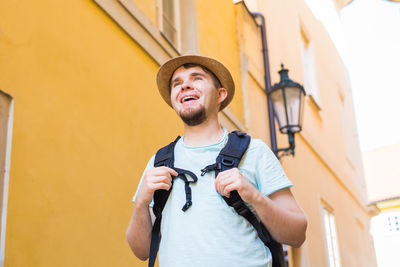 Young man looking away while standing against built structure