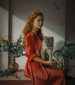 Young woman with cat sitting in a room