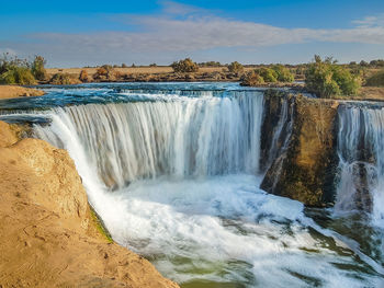 Scenic view of waterfall against sky