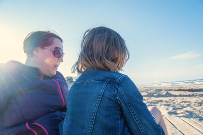 Friends enjoying at shore against sky